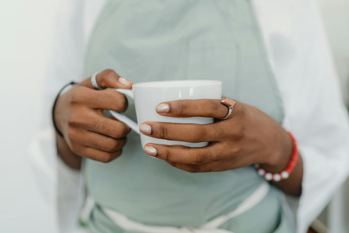 A barista wearing an apron holds a white coffee mug, showcasing contemporary café culture.