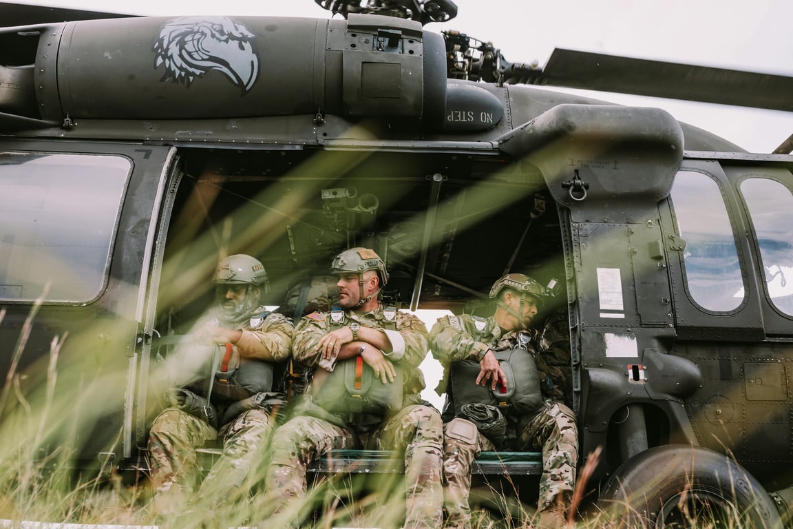 Soldiers seated inside a military helicopter ready for a mission outdoors.