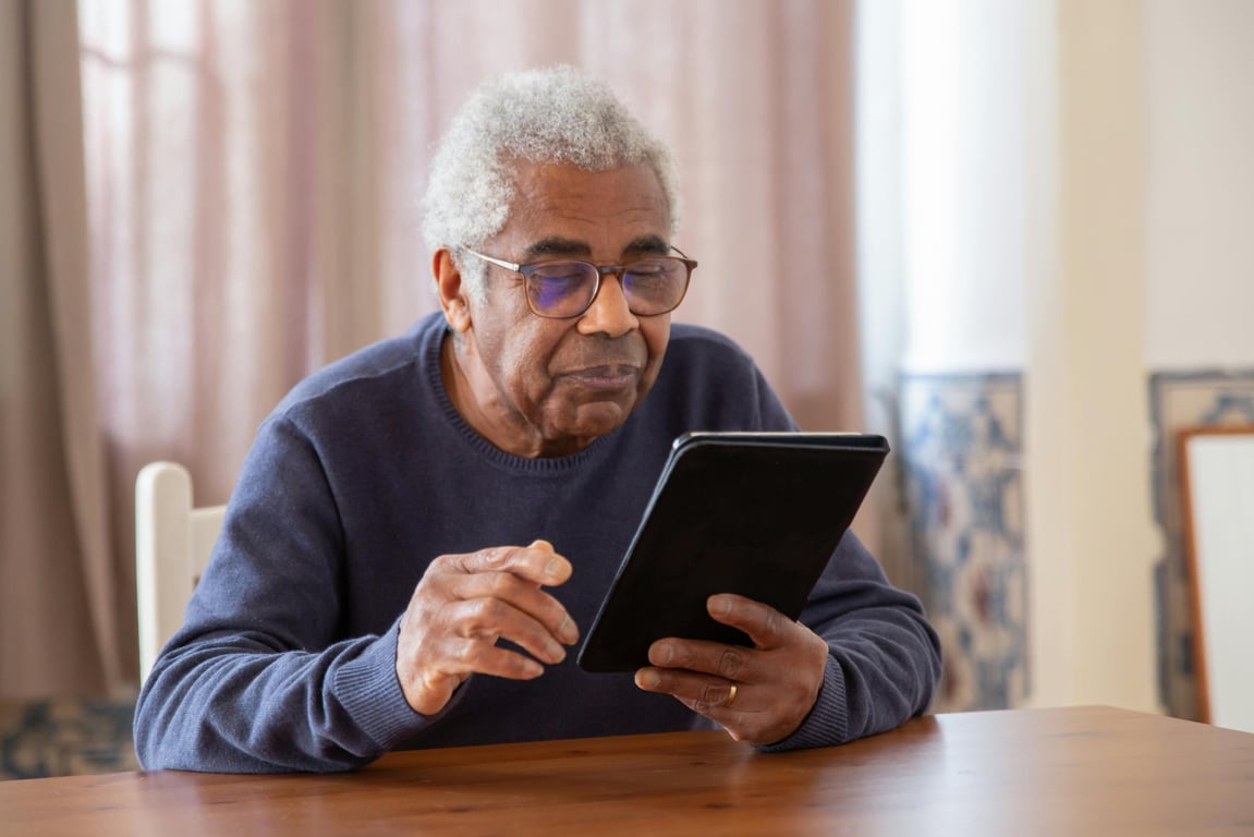 Senior man using a digital tablet indoors, focusing on modern technology and connection.