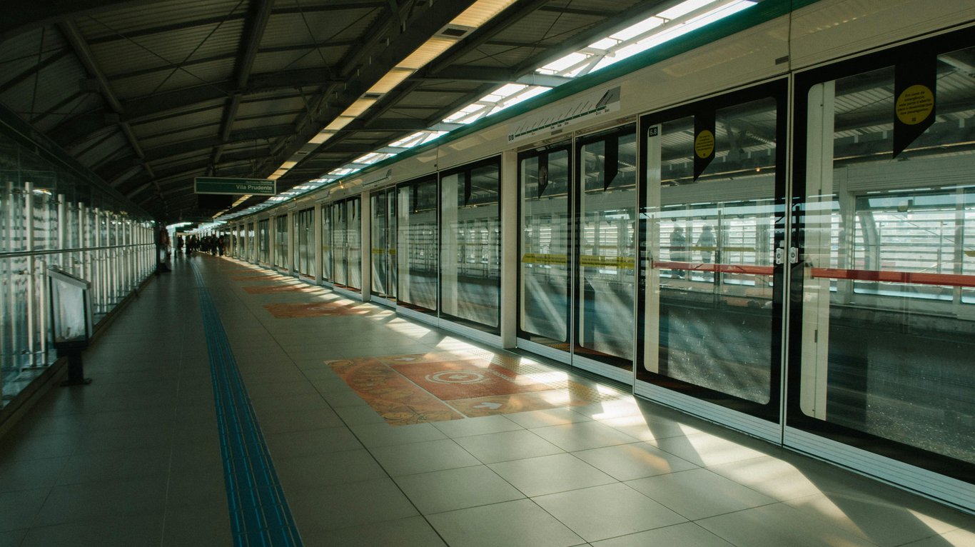 A contemporary subway station interior with glass panels and natural light streaming through the windows.