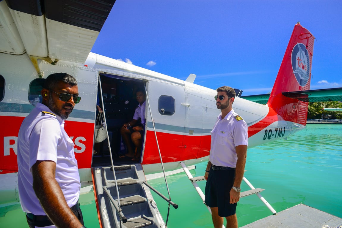 Seaplane pilots prepare for flight on a sunny day, showcasing vibrant tropical waters.