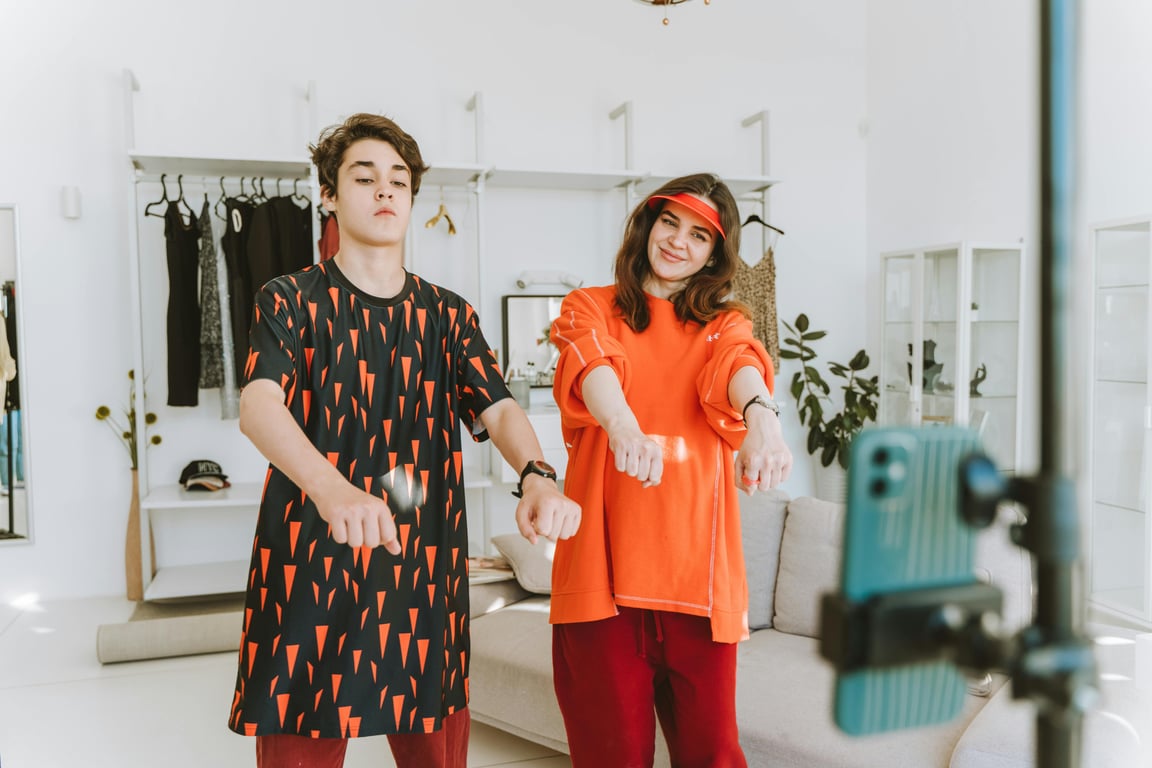 A mother and her teenage son dancing together indoors, showcasing fun and family bonding.