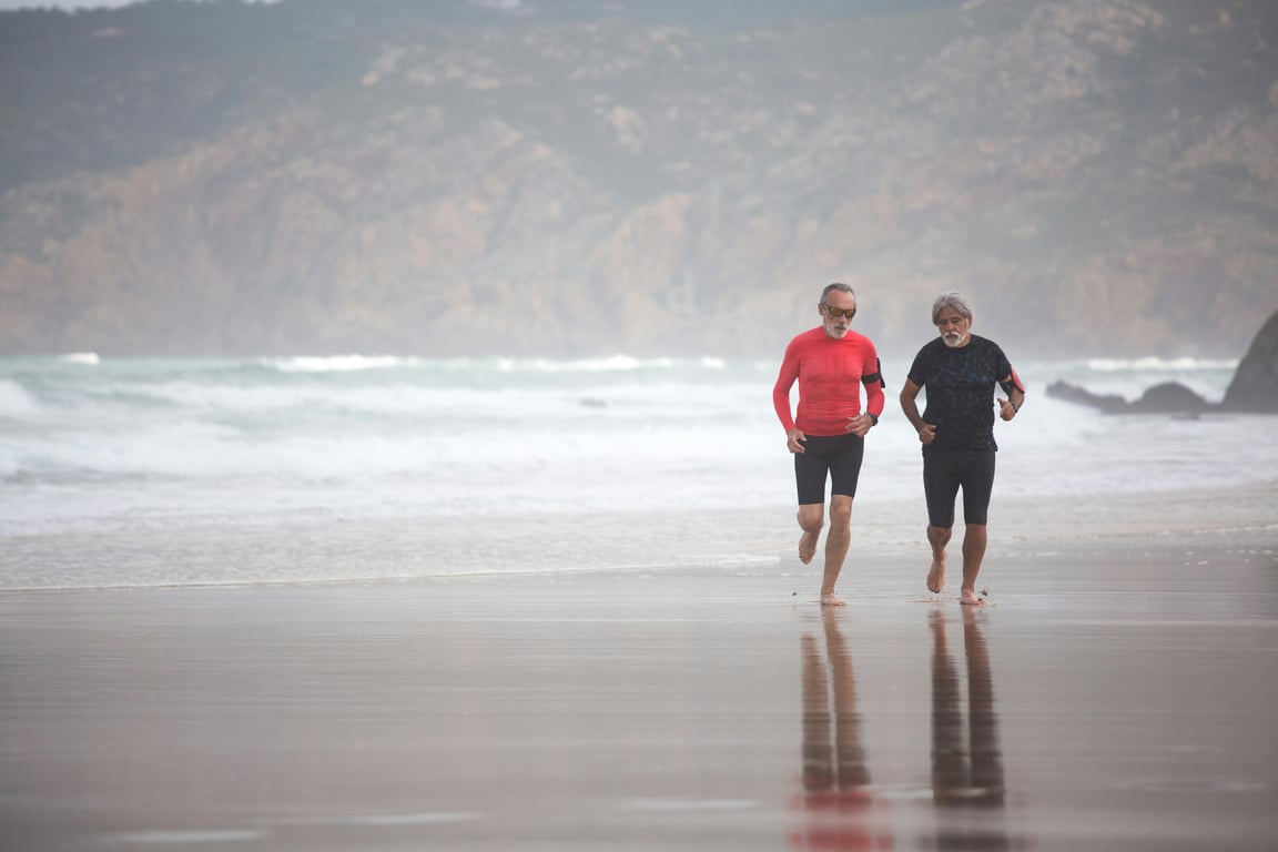 Elderly men jogging on a scenic beach in Portugal, embodying fitness and healthy living.