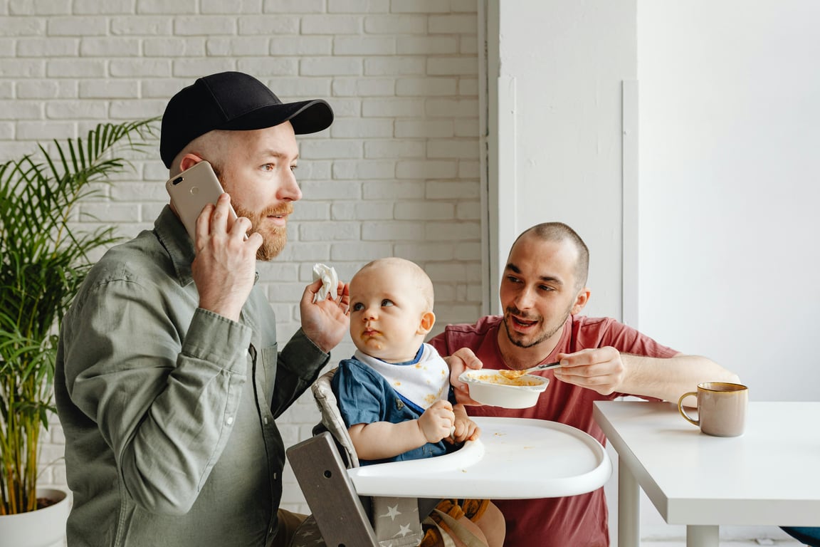 Two men and a baby during breakfast indoors. A heartwarming family moment.