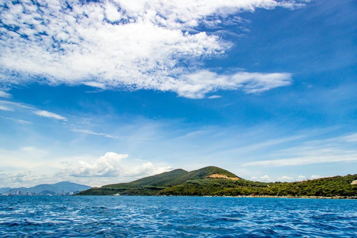 Breathtaking view of an island with lush greenery surrounded by clear blue ocean under a bright sky.