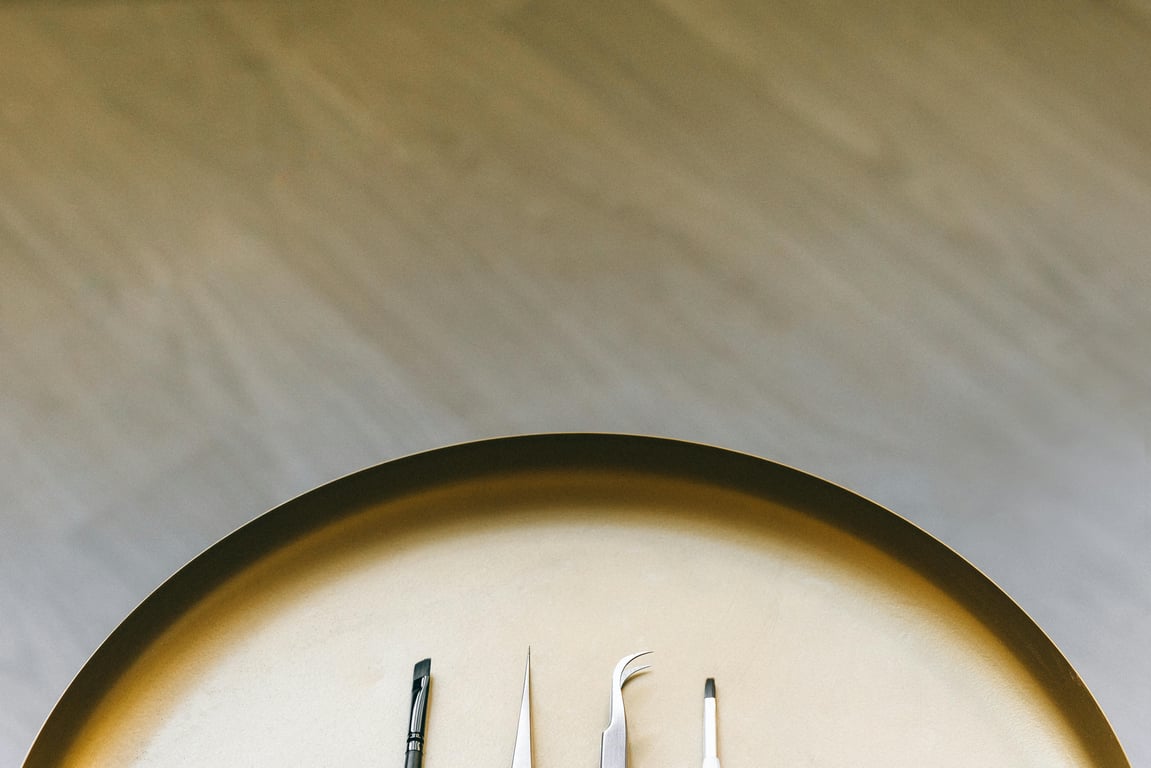 Flat lay arrangement of makeup tools on a gold plate provides a chic and minimalist aesthetic.