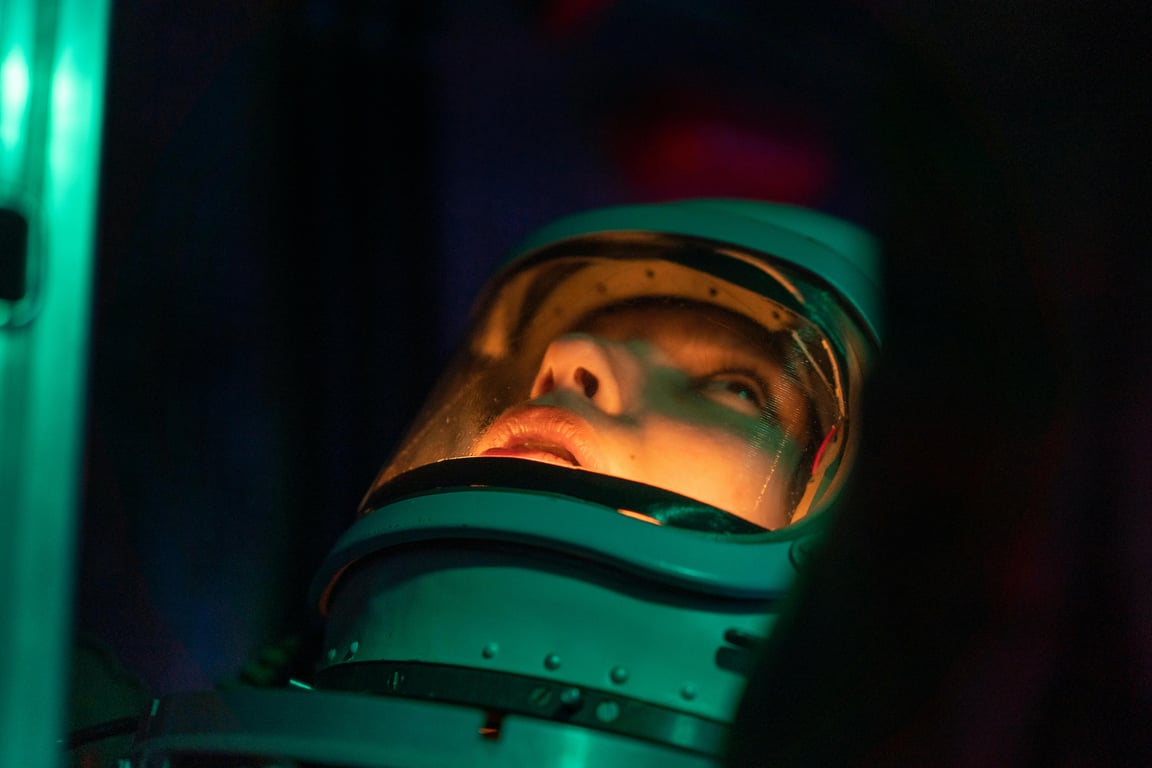 A futuristic spacewoman in a helmet looks up contemplatively, creating a sci-fi atmosphere.