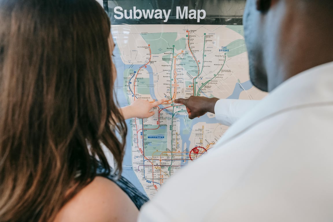 A couple examines a subway map, planning their route at a station.