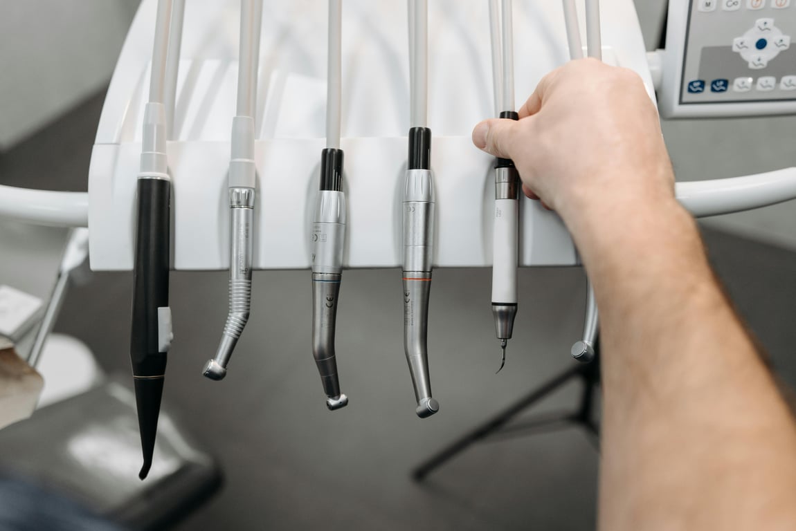 A close-up view of dental instruments being held by a hand, showcasing modern dental equipment.