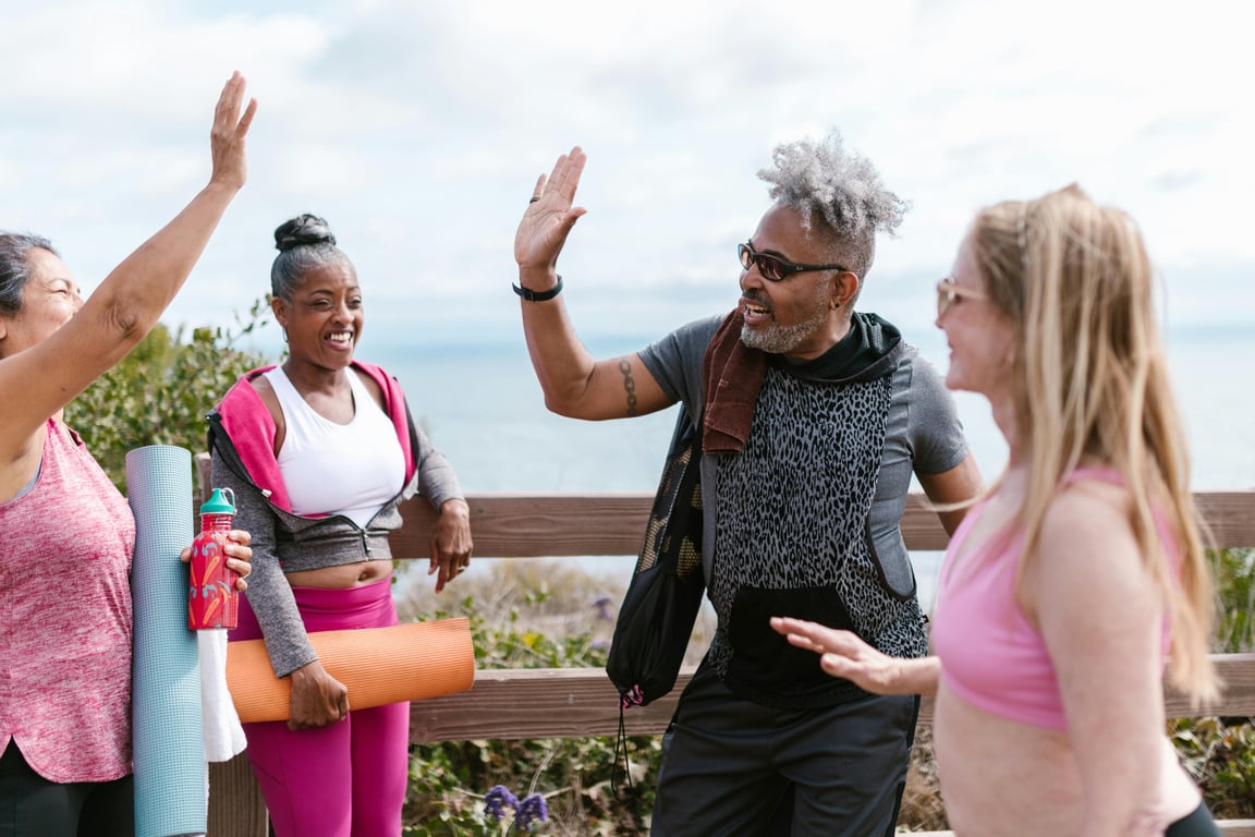 Group of senior adults sharing a joyful outdoor yoga session near the sea.