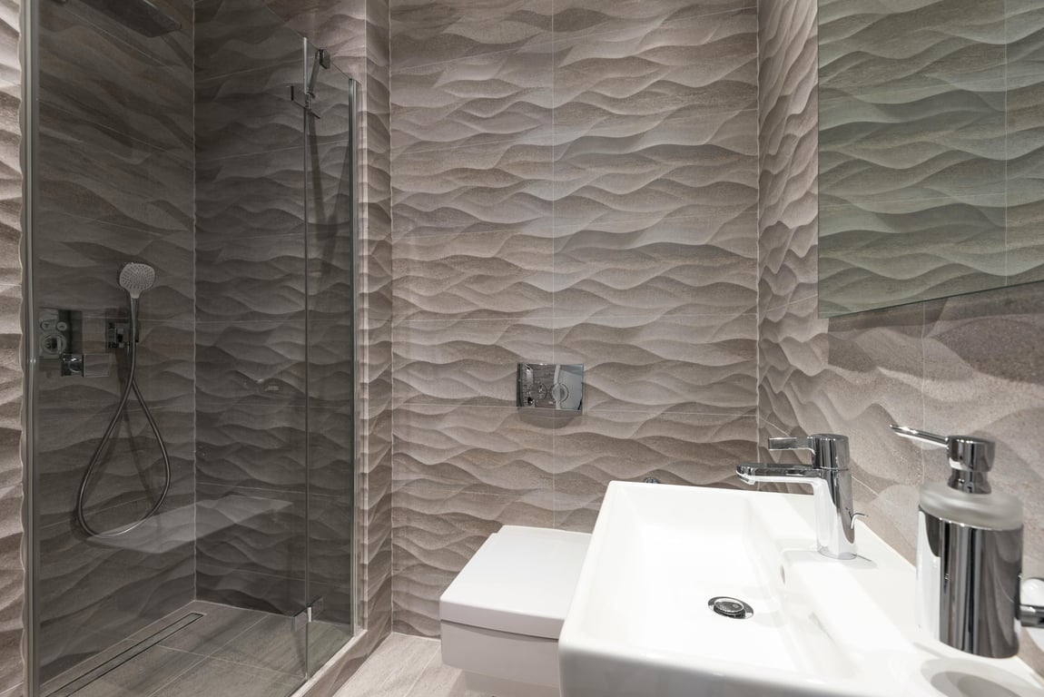 Contemporary bathroom featuring wave-patterned tiles, glass shower, and modern fixtures.