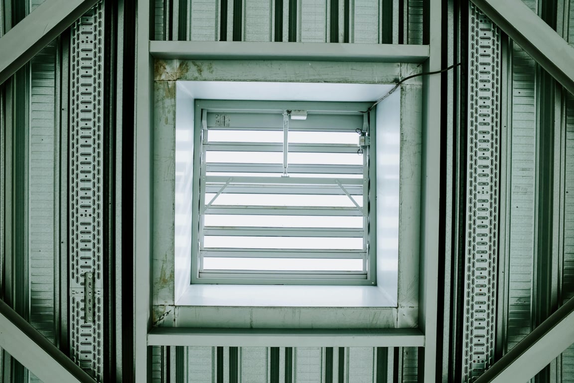 Modern architectural ceiling structure featuring a metallic ventilation grid.