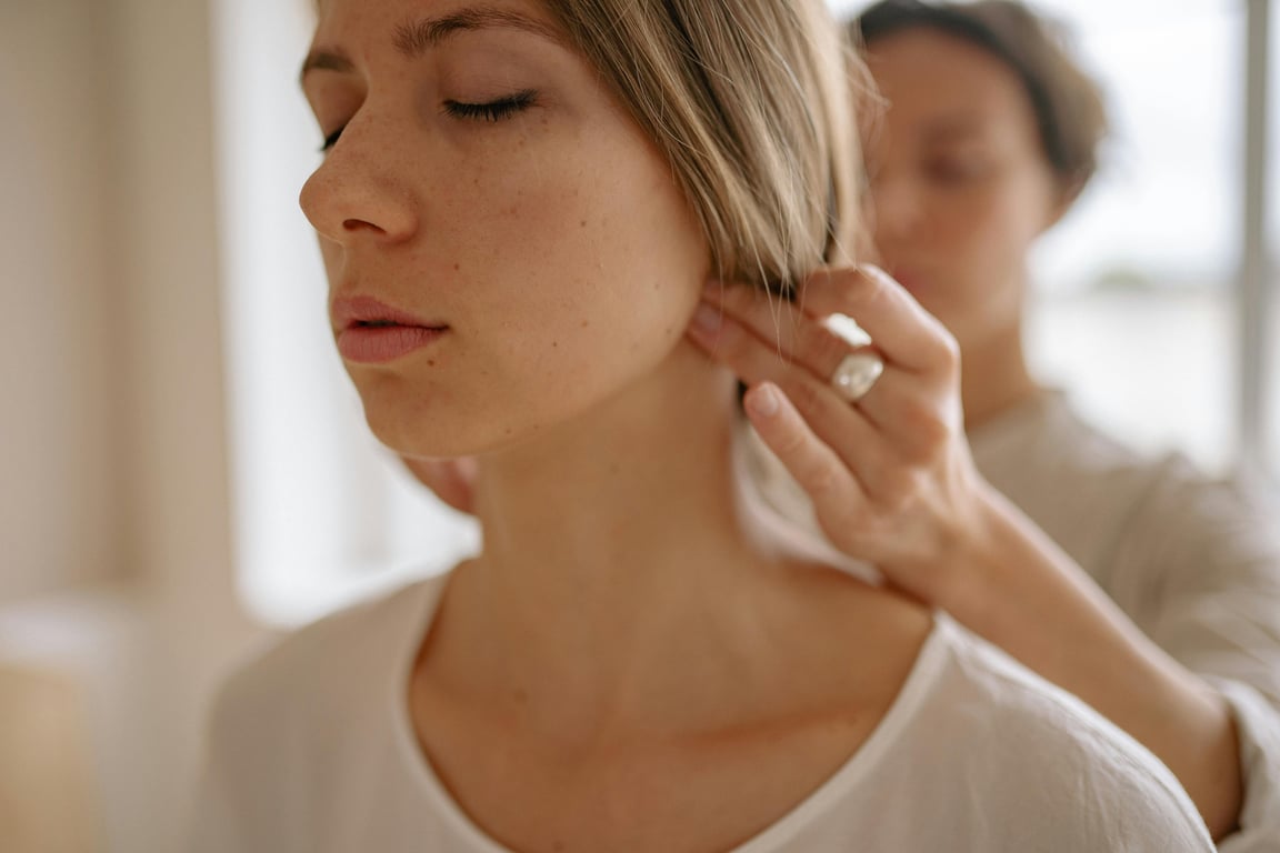 Close-up of a woman receiving a soothing neck massage in a calm indoor setting.