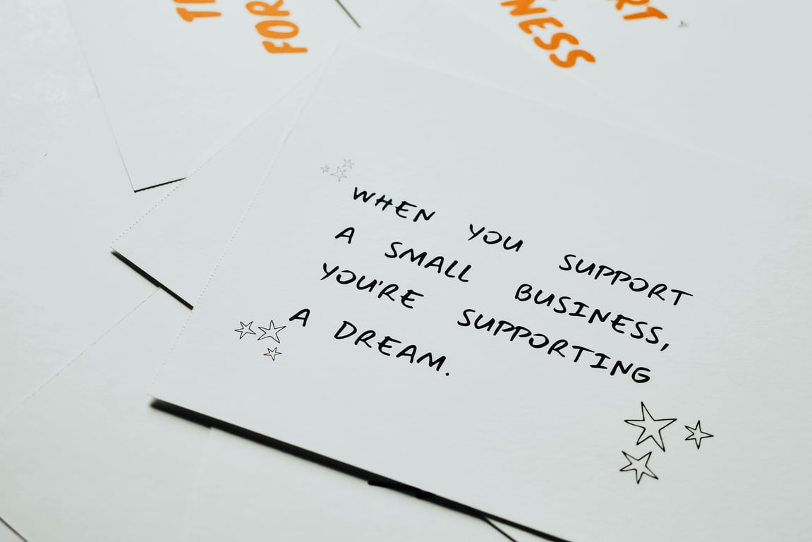 Motivational note on white paper about supporting small businesses with decorative stars.