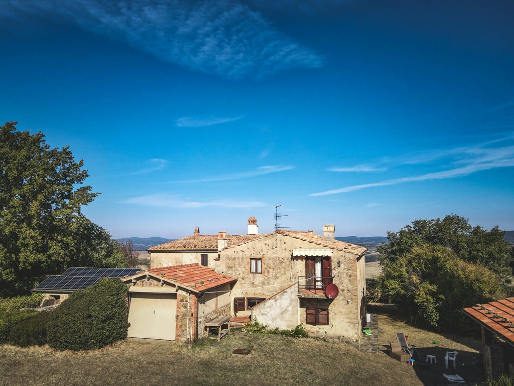Beautiful rustic house with solar panels amidst nature under a clear blue sky. Perfect for sustainable living.