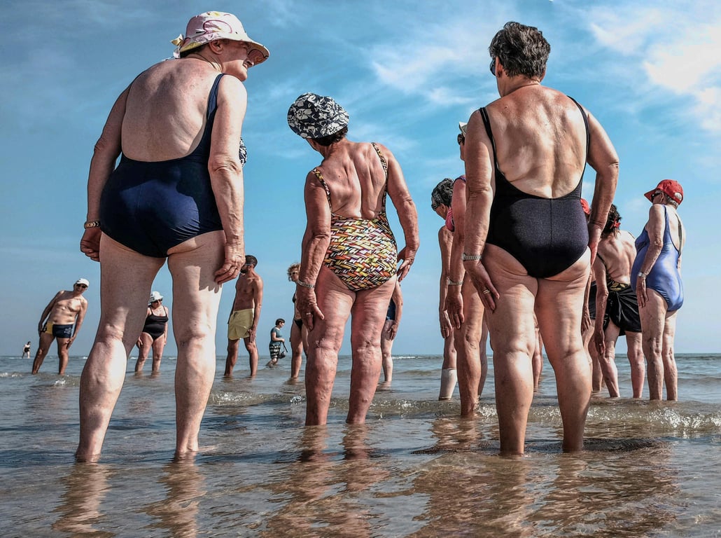 Senior adults gathered on the beach, enjoying a sunny day by the sea.