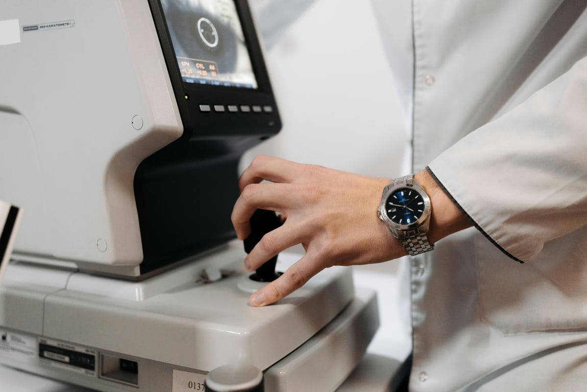 A doctor's hand operating an eye examination device in a clinical setting.