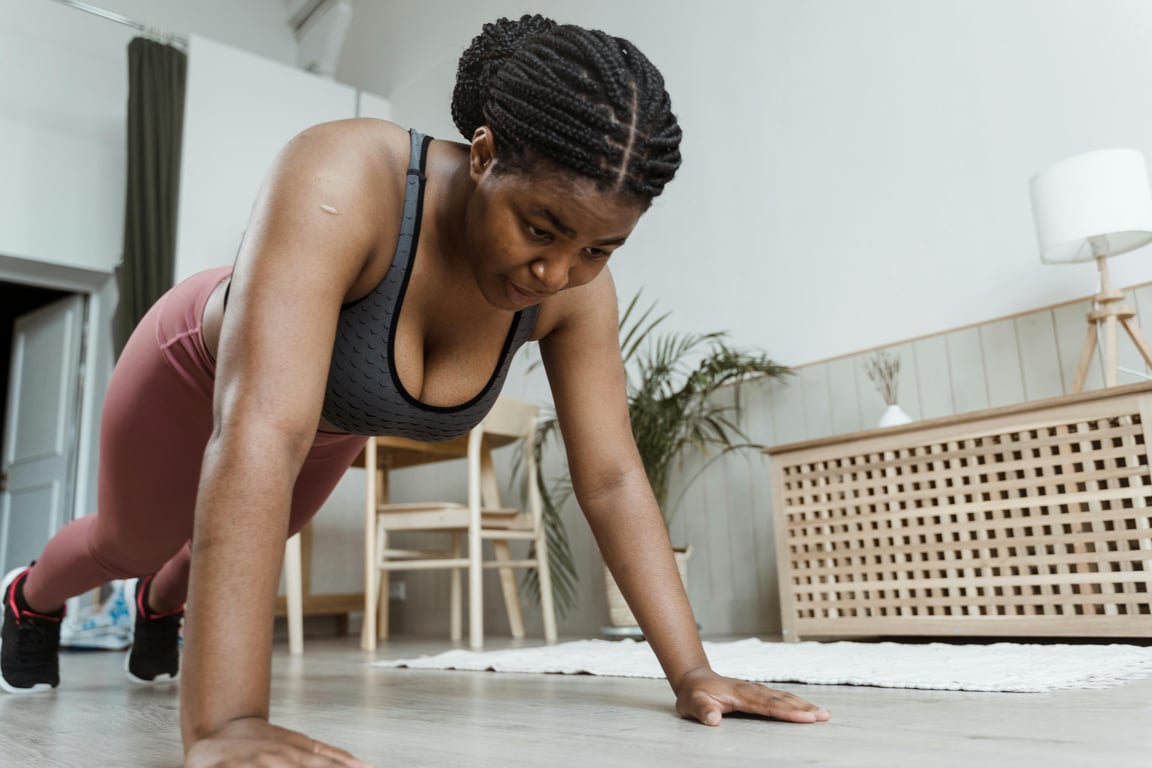 Plus-size woman performing push-ups indoors, emphasizing fitness and healthy living.