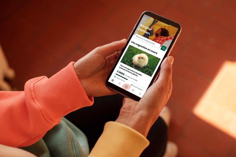Une personne tenant un téléphone avec l'application mobile Leetchi
