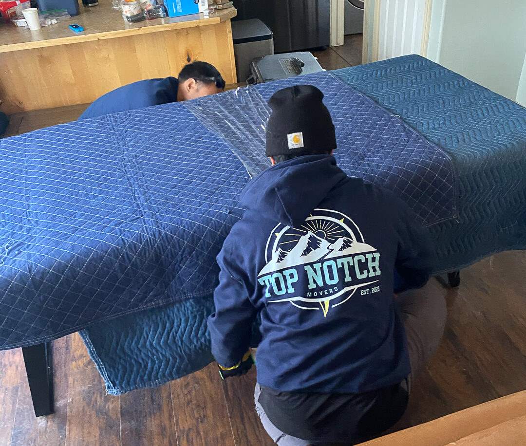 A Top Notch mover wrapping furniture in moving blankets