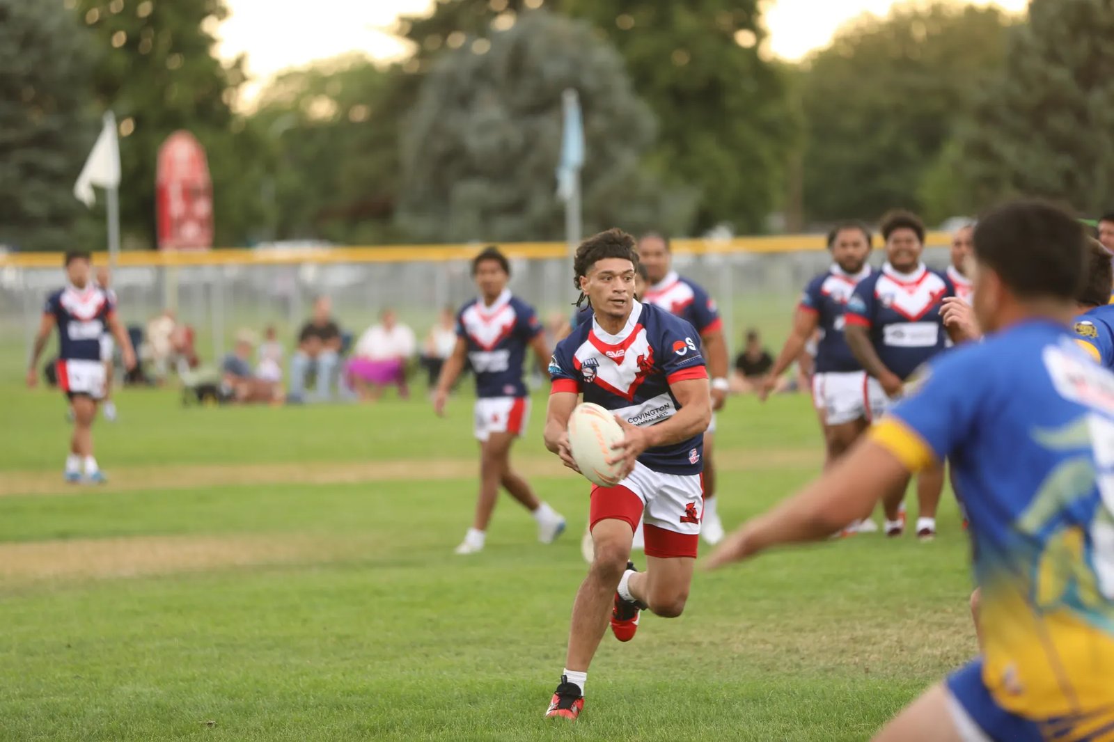 A Roosters player running with the ball mid-match