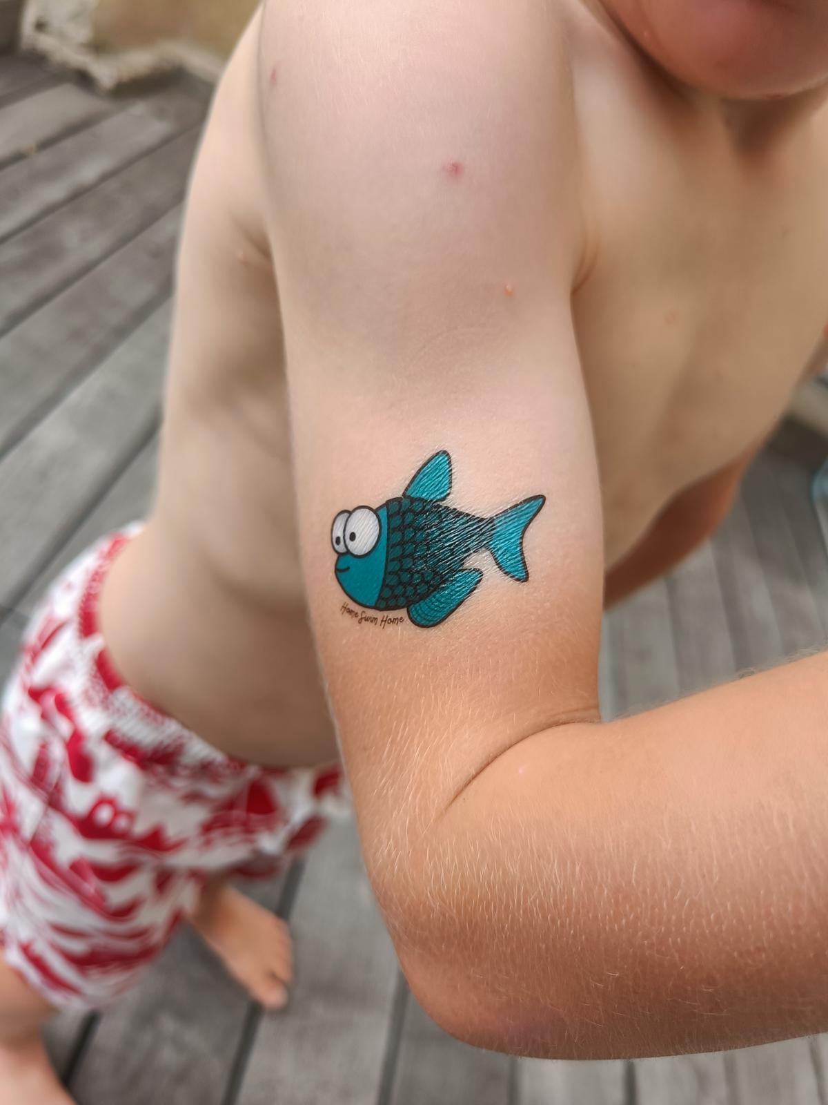 Un tatouage éphémère poisson Home Swim Home sur le bras d'un enfant