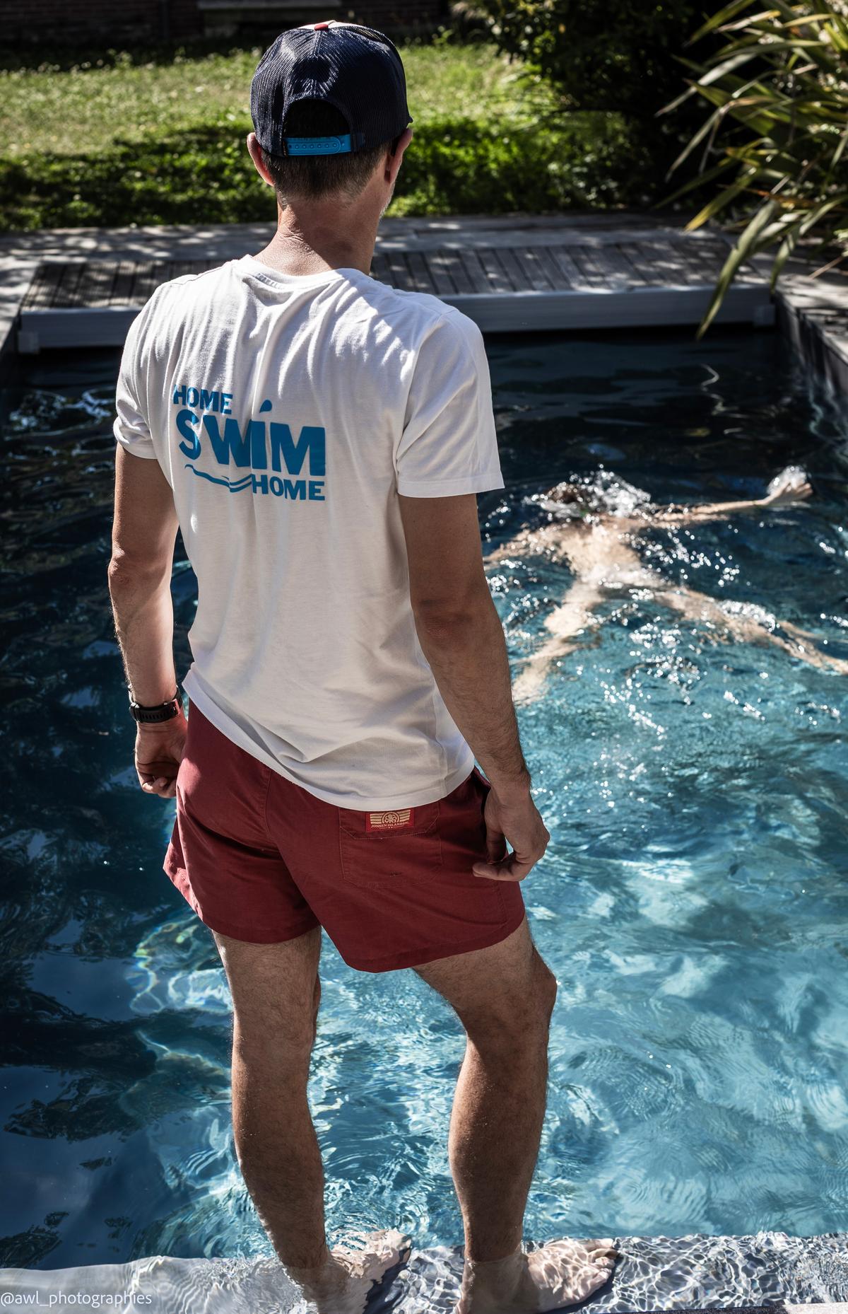 Un maître-nageur Home Swim Home, debout sur les marches de la piscine, surveille un enfant qui flotte