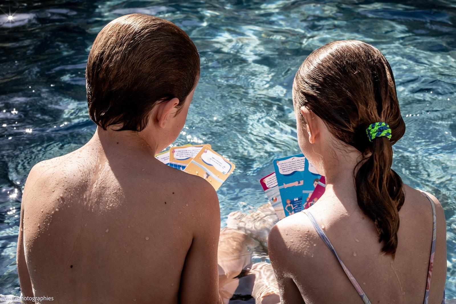 Deux enfants lisent leurs cartes au bord de la piscine