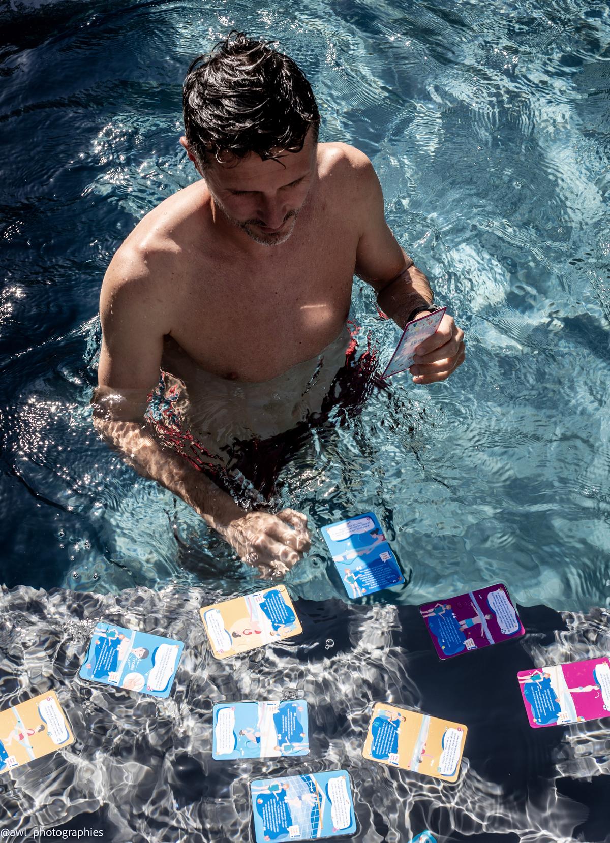 Fabien dans la piscine, entouré des cartes étanches qui flottent