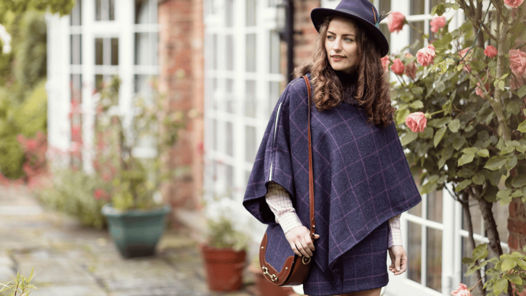 Woman styling a navy tweed poncho, checked shirt and felt hat for an autumn country wedding.