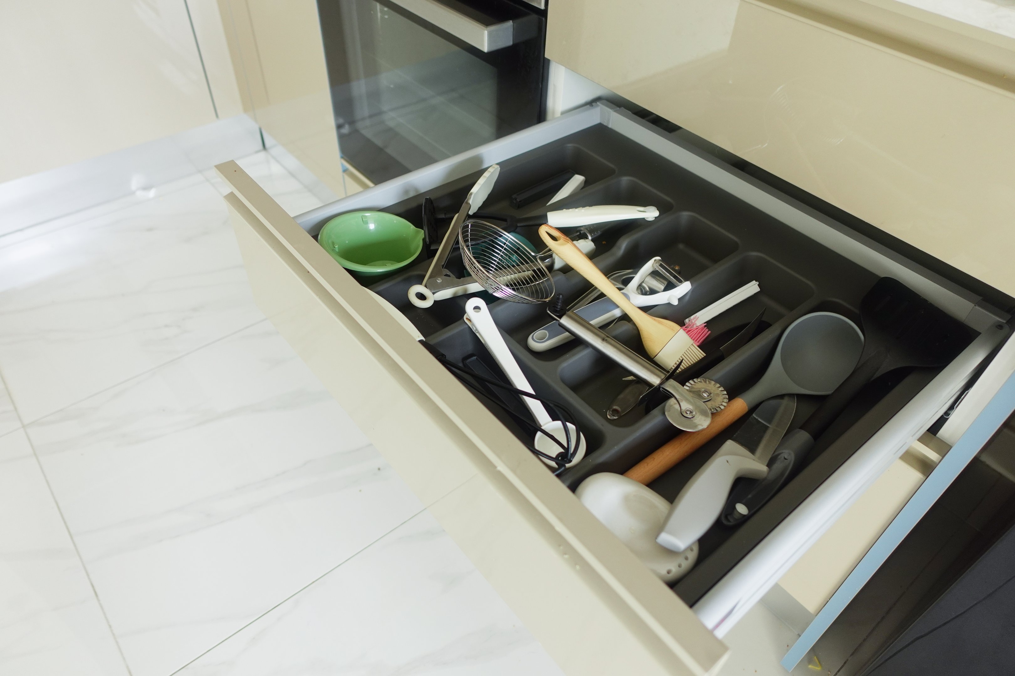 Utensils sorted in a kitchen drawer divider tray to keep tools separated and easy to find.