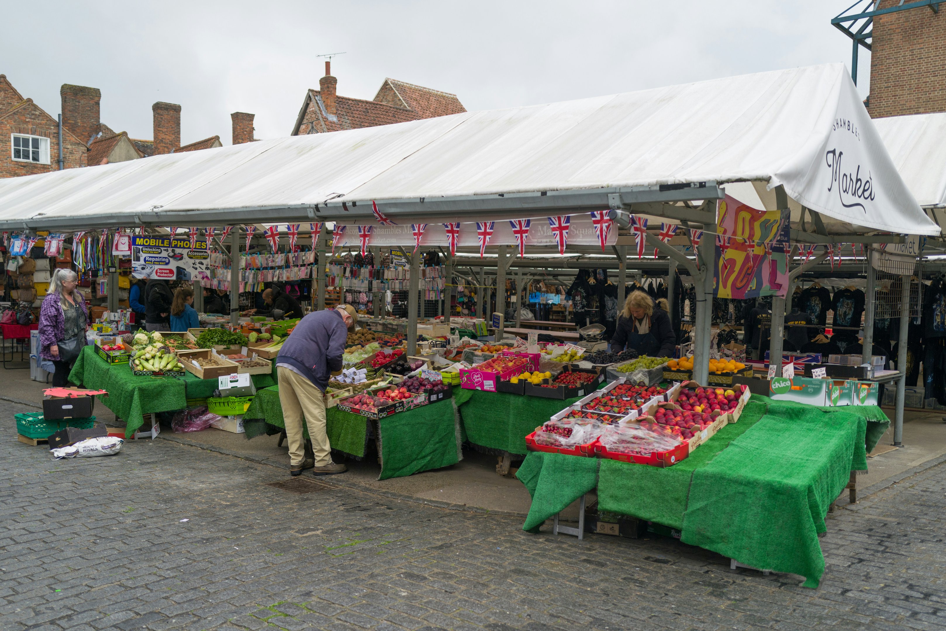 Étal de marché en plein air à York vendant des fruits et légumes frais sous un auvent couvert.