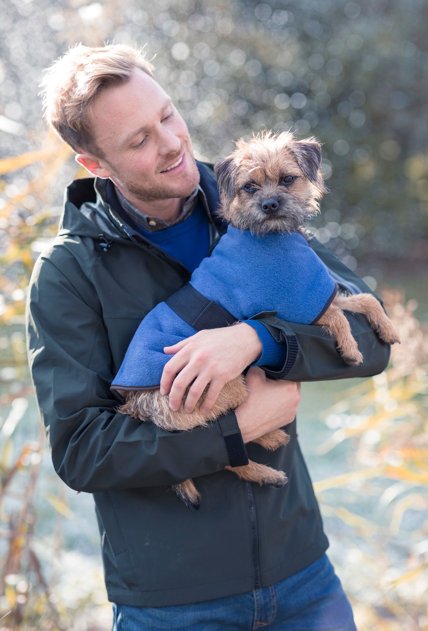 Man holding dog wearing fleece coat