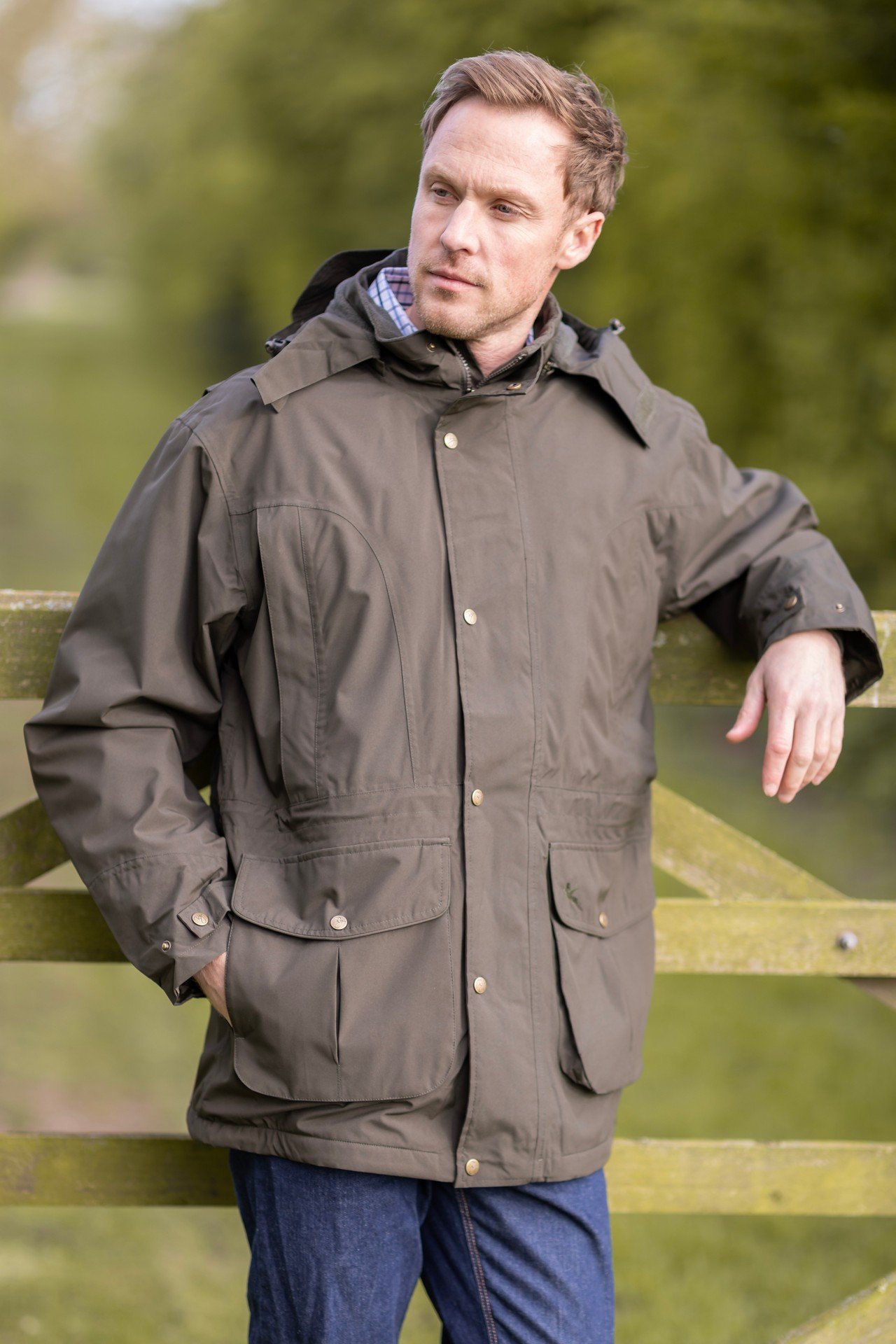 Mann mit wasserdichter Jacke auf einem Feld.