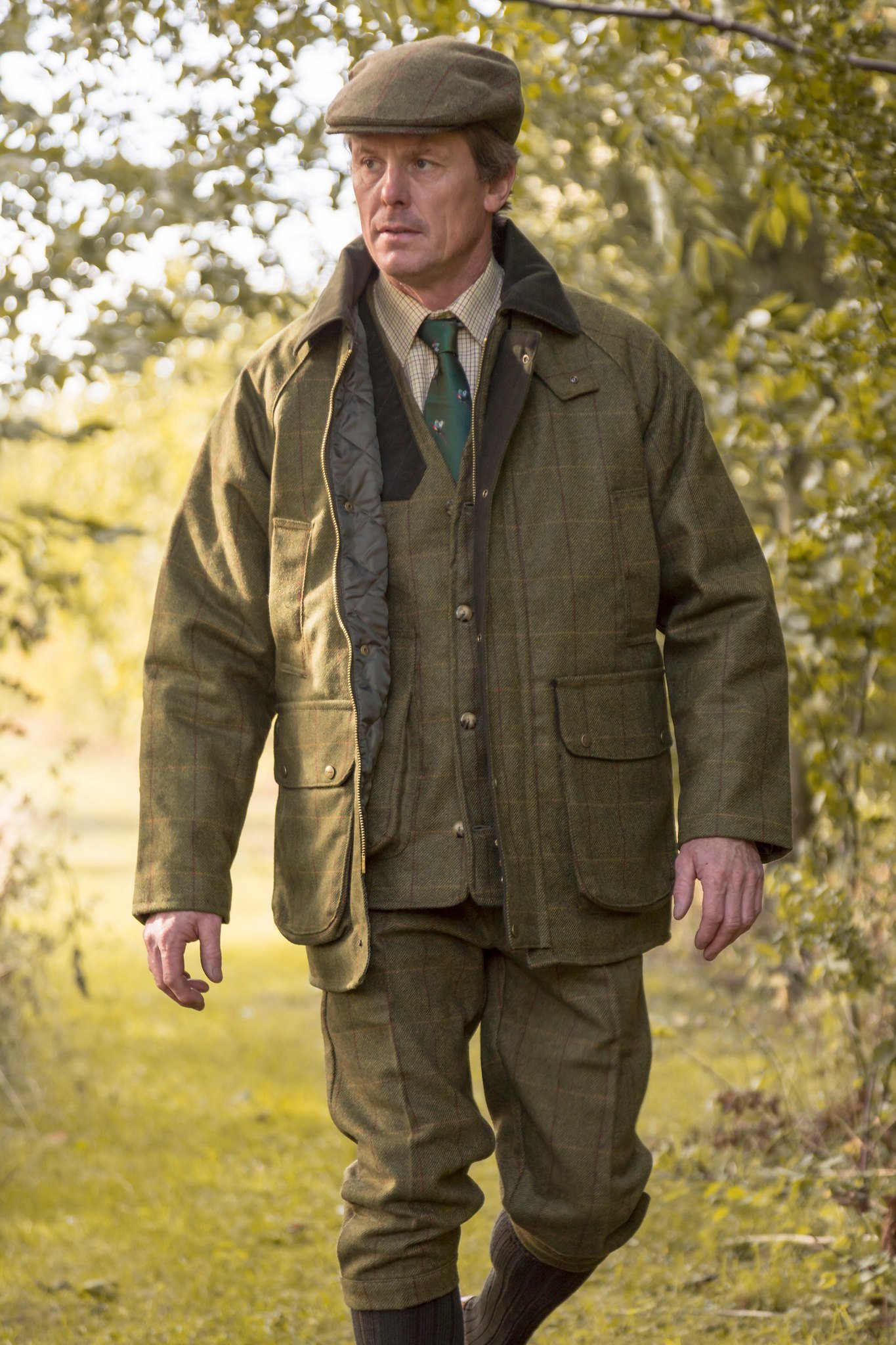 Man wearing a tweed jacket layered with a shirt and waistcoat.