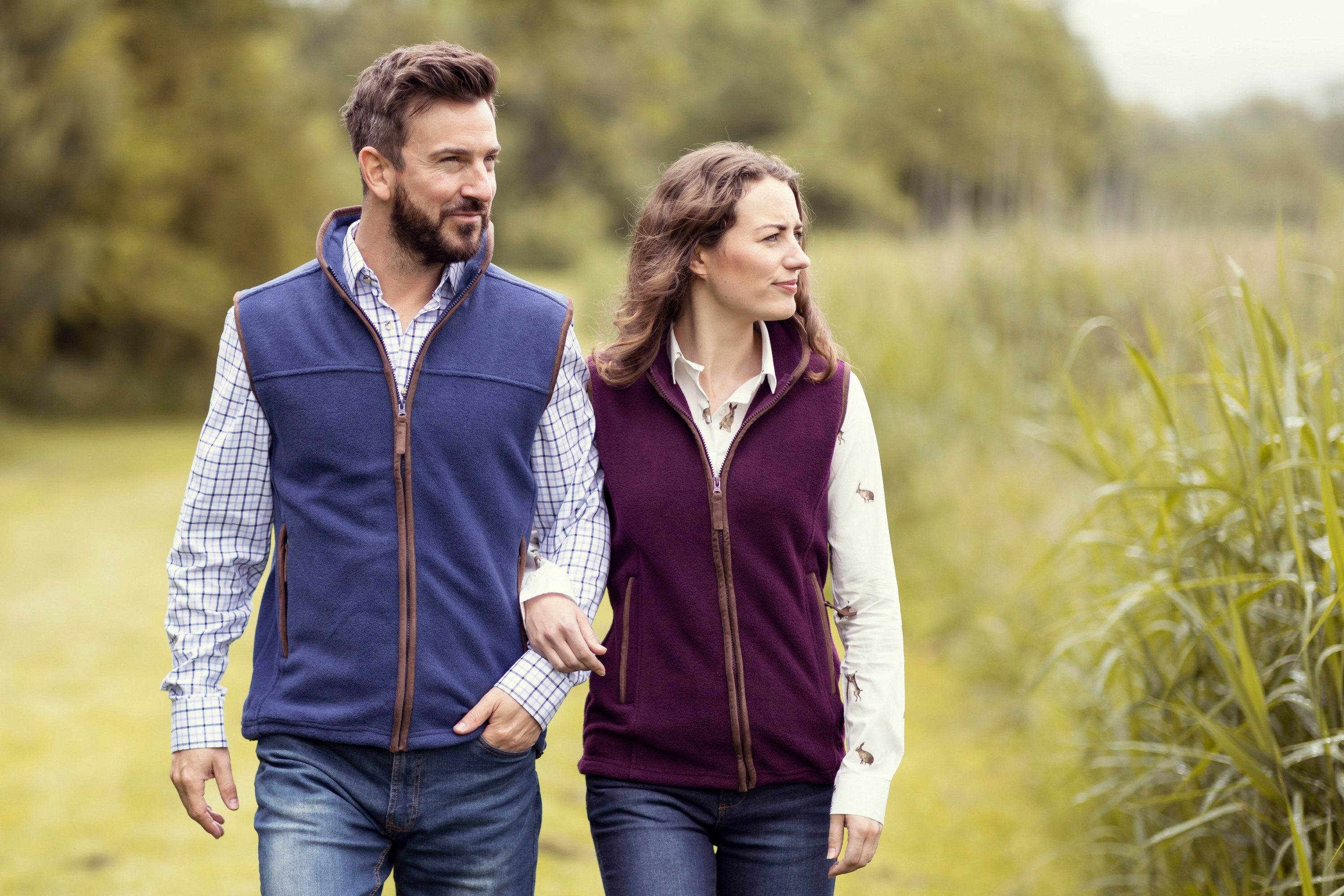 Un homme et une femme marchent à l'extérieur, vêtus de gilets polaires bleus et bordeaux.