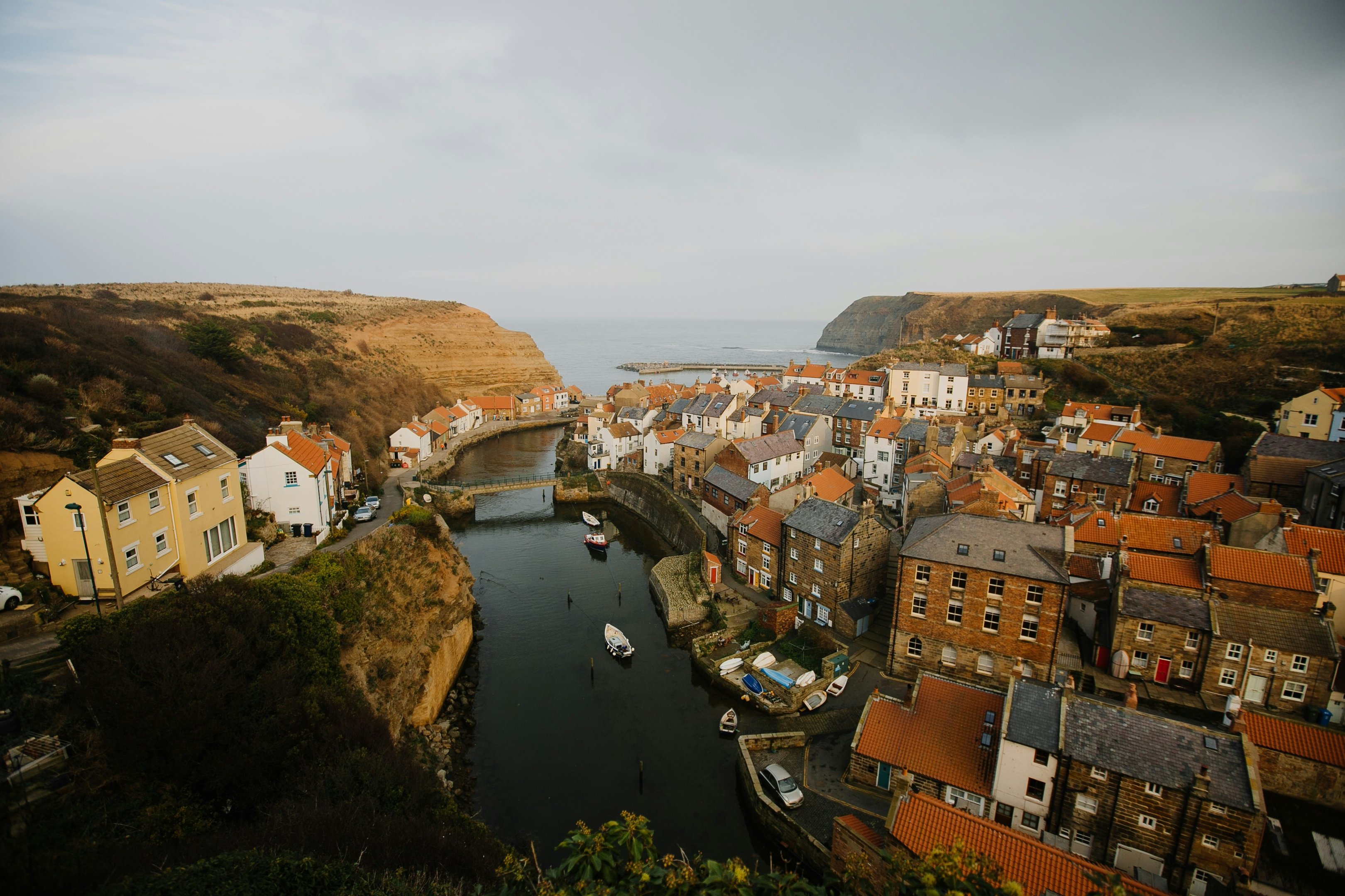 Vue sur Staithes, sur la côte du Yorkshire, avec ses maisons groupées, son port et ses falaises.