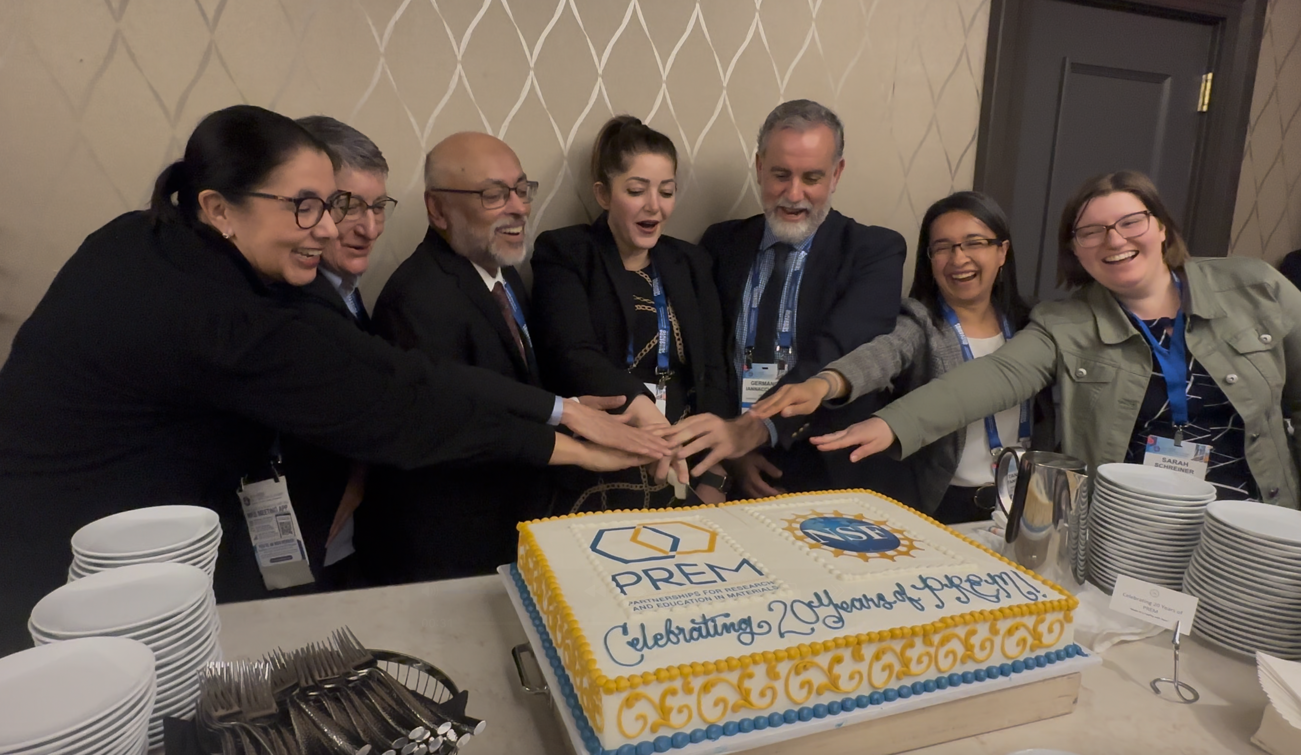 PREM members of the community along with program directors prepare to cut a cake to commemorate the 20th anniversary of the PREM program.
