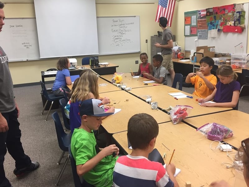 Nebraska MRSEC undergraduates Spencer Prockish (left) and Peter Kosch help elementary students design their own experiments to determine how a magnet’s size and shape affect its strength.
