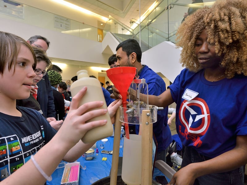 Damilola Lawal, from the Raney lab, demonstrates The Utility of Instability to a K-12 student. Image source: Felice Macera
