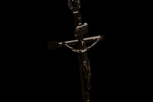 Close-up detail of a silver crucifix pendant showing the corpus figure and INRI tablet inscription at the top of the cross