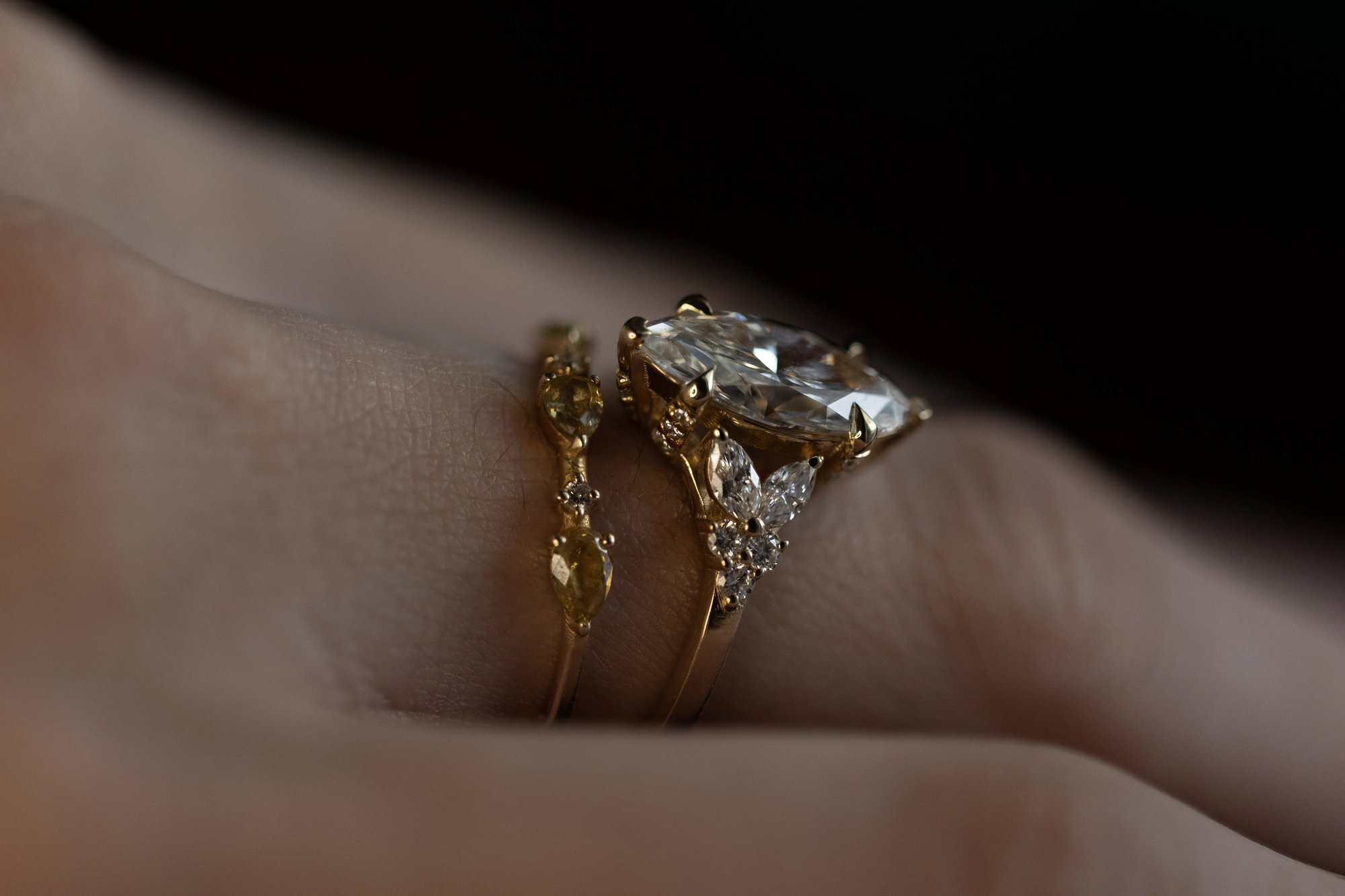 Marquise diamond ring in yellow gold, three-quarter view on a dark background showing the stone face and band shoulders