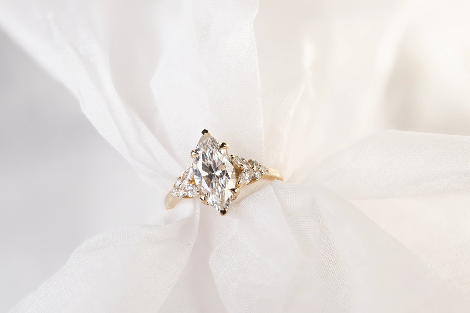 Marquise diamond ring in yellow gold, close view of the marquise stone and prong setting against a dark background
