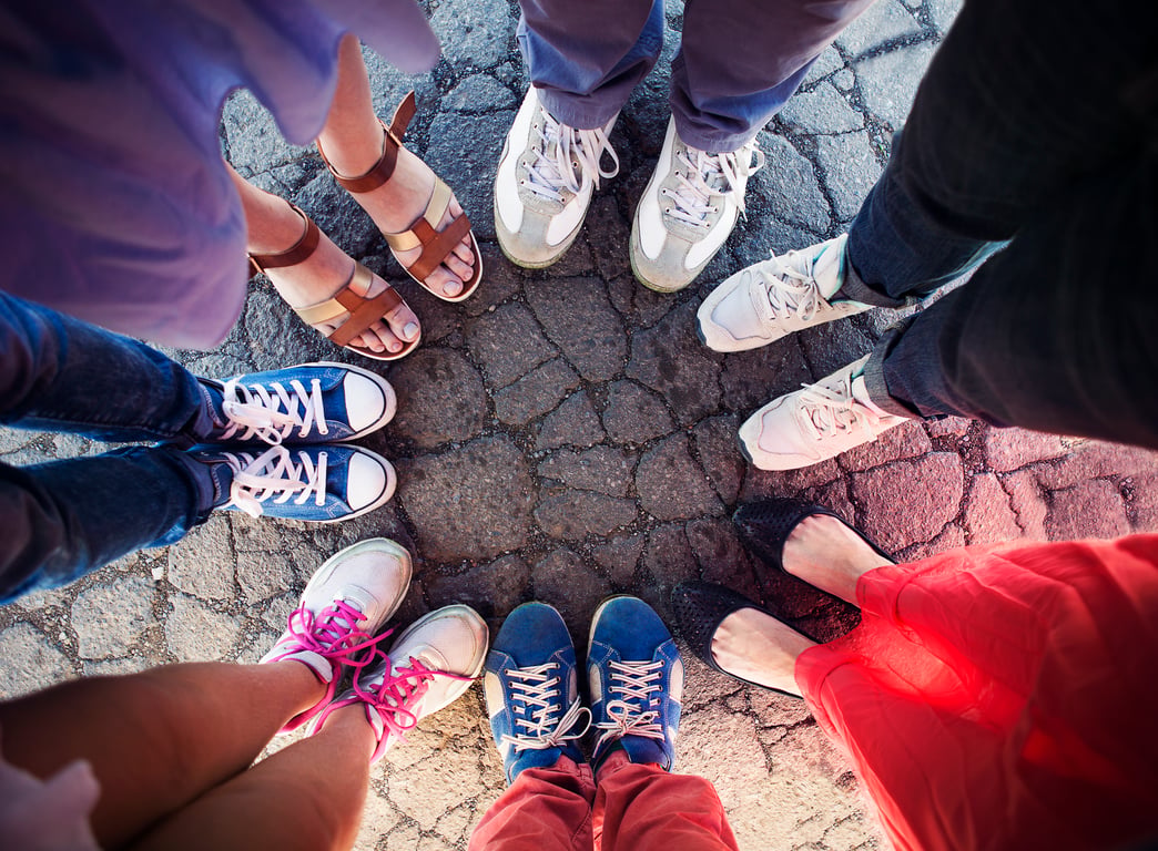 A circle of walking shoes from above — many feet, gathered together