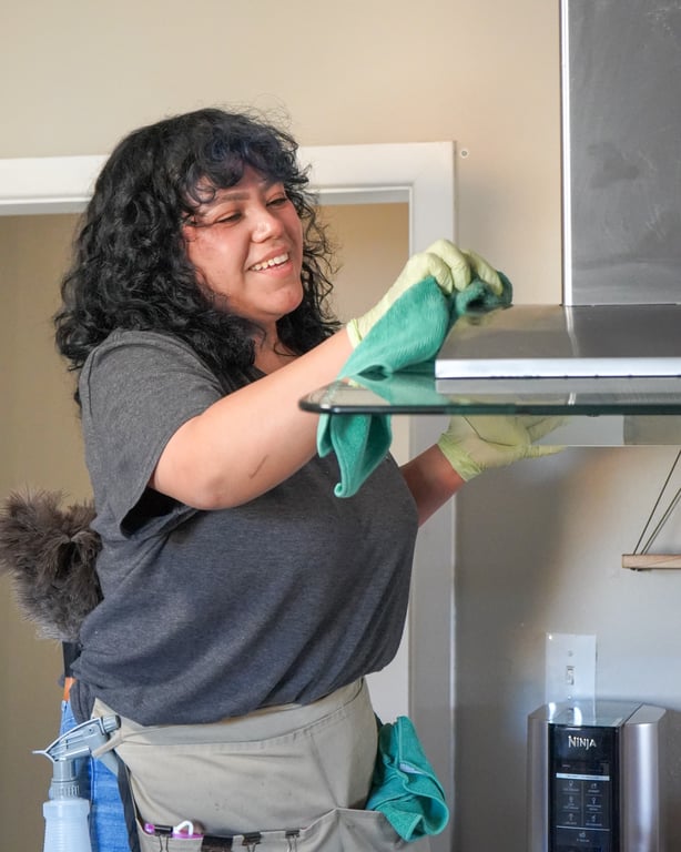 Smiling cleaner wiping a kitchen range hood