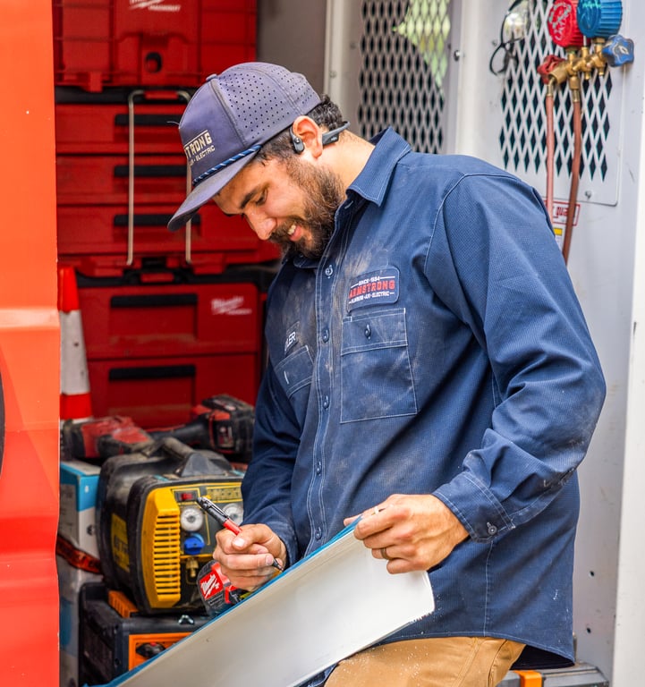 Technician marking a piece of sheet metal beside a work van