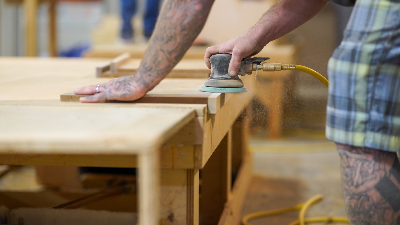 Close-up of a worker sanding a cabinet