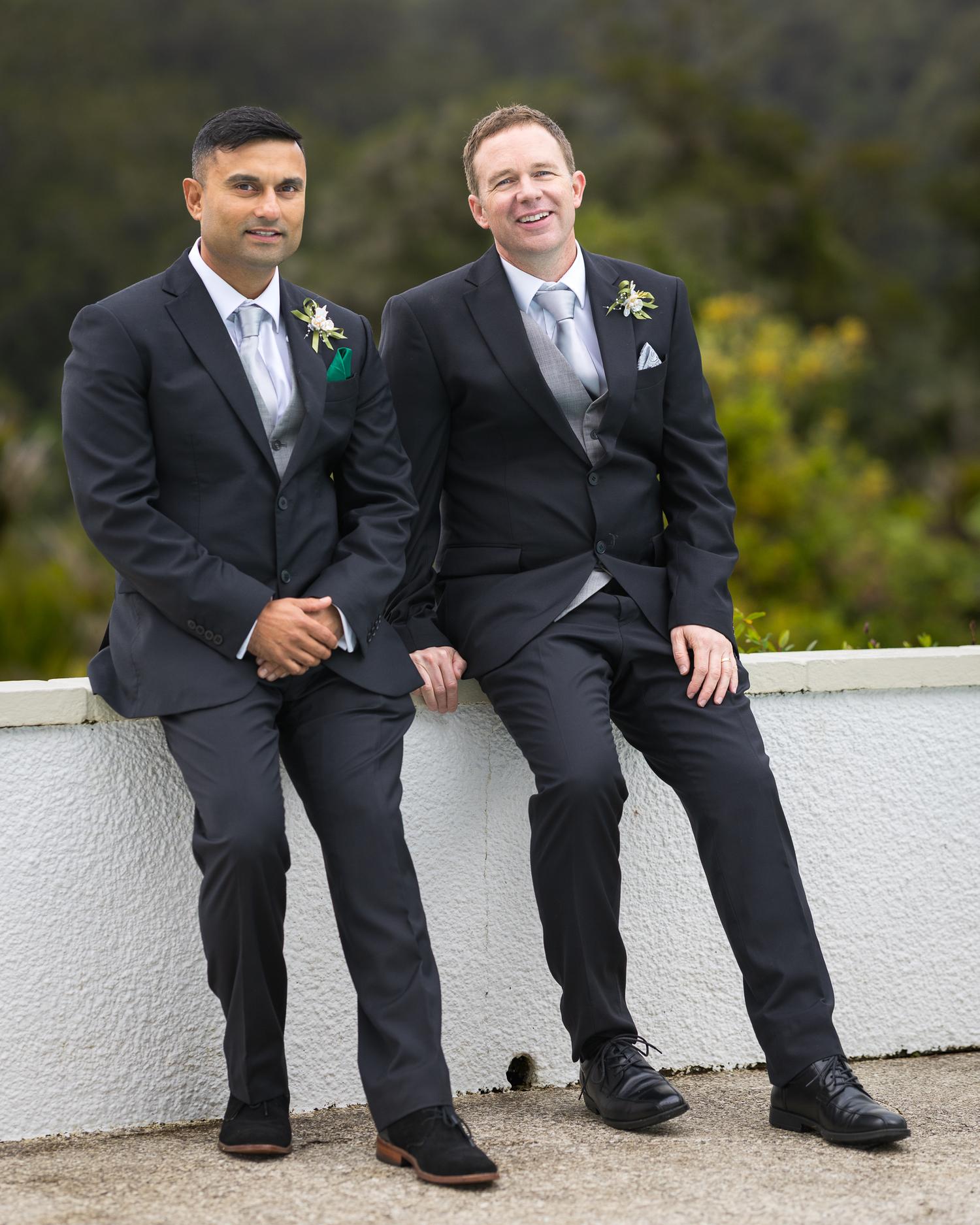 Steven and his best man sit on a white wall