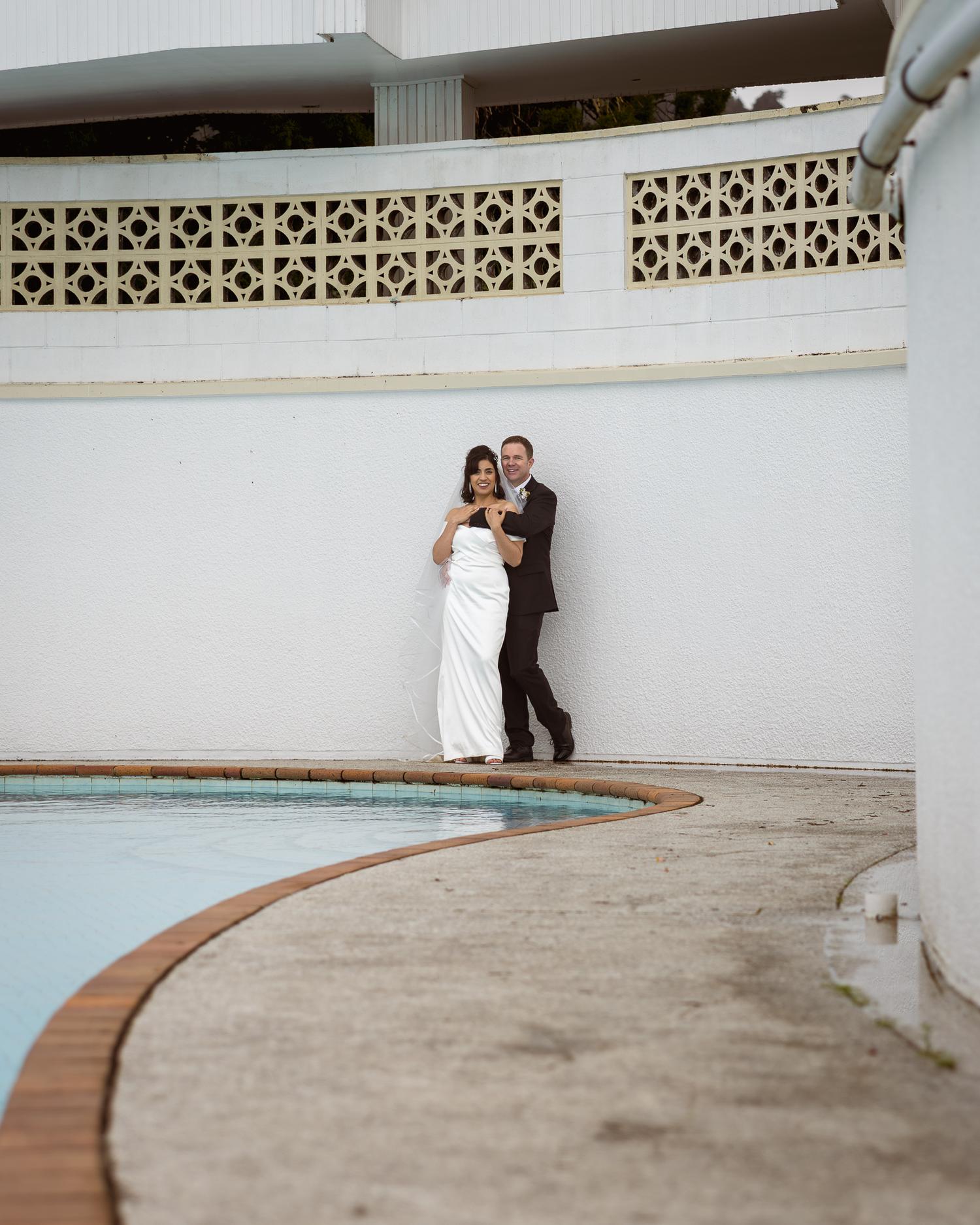 Feby and Steven embrace beside the curved pool
