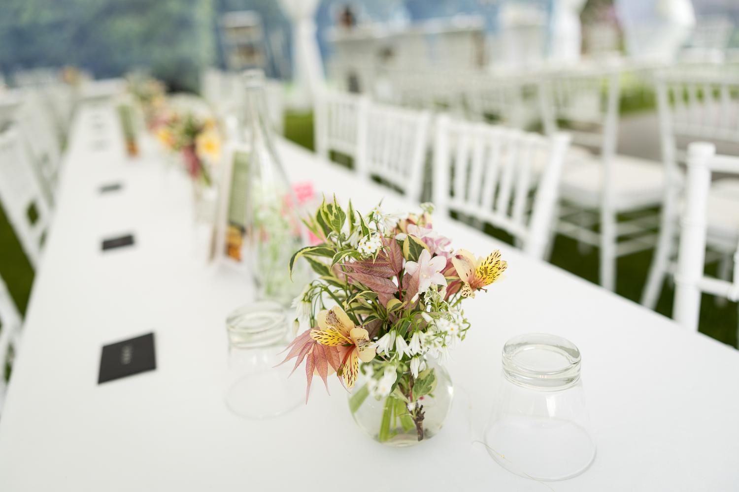A reception table set with flowers in the marquee
